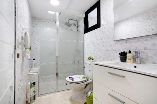 a white bathroom with a shower and a toilet at Casa del Sol Rosa in Corralejo