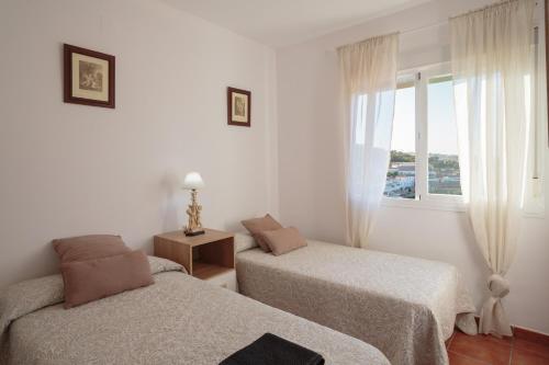 two beds in a white room with a window at El Balcón de la Sierra in Seville