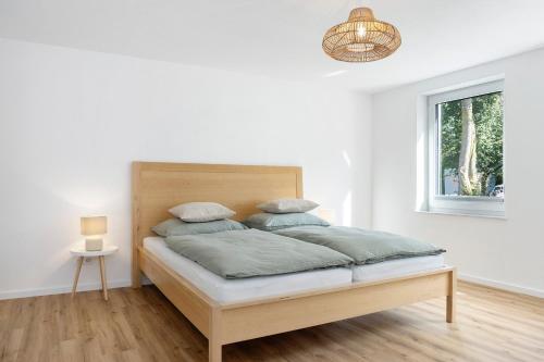 a white bedroom with a bed with a wooden headboard at Ferienwohnung Götz in Roßhaupten