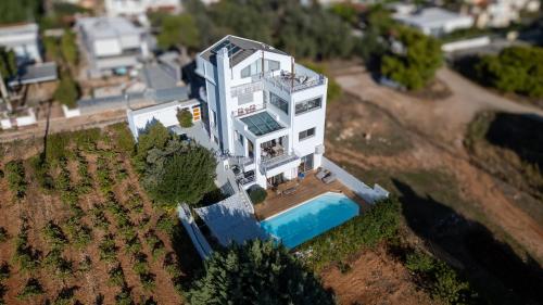 a large white building with a pool in front of it at Evaeri villa in Artemida