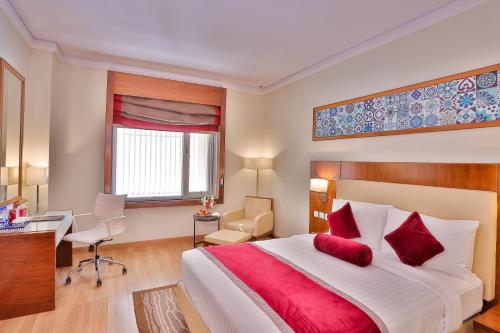 a bedroom with a large bed with red pillows at Avari Xpress Multan in Multan