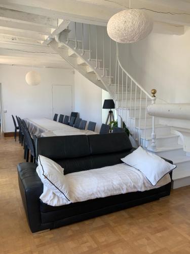 ein Wohnzimmer mit schwarzem Sofa und Treppe in der Unterkunft La Béchetière in Parcé-sur-Sarthe