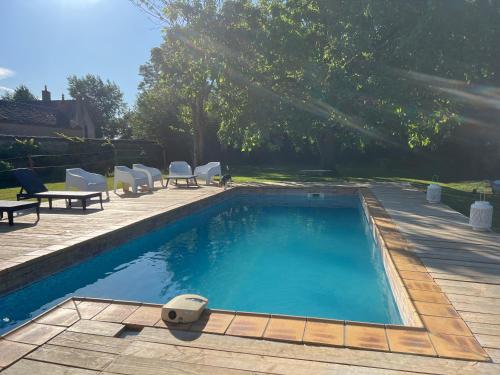 ein Swimmingpool im Garten mit Stühlen und Tischen in der Unterkunft La Béchetière in Parcé-sur-Sarthe