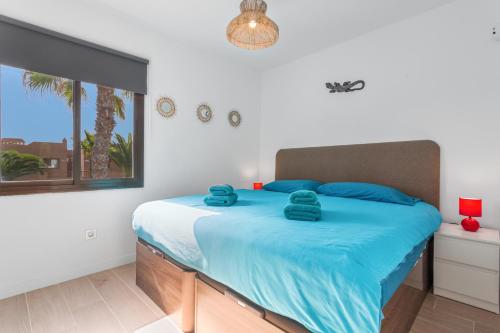 a bedroom with a bed with blue sheets and a window at Brisa Azul in Corralejo