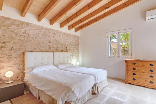 a bedroom with a large white bed and a window at Possessio Sa Barrala Gallinero in Campos