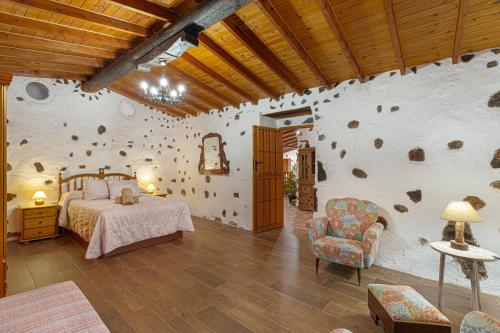 a bedroom with a bed and a rock wall at Casa Las Toscas in Ingenio