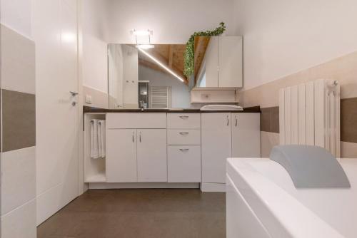 a white kitchen with white cabinets and a sink at Luxury Lakefront Maisonette in Lezzeno