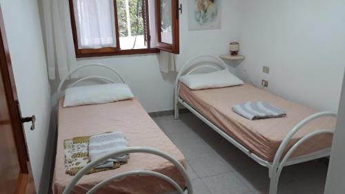two twin beds in a room with a window at Apartments Porto Ottiolu Mare in Porto Ottiolu