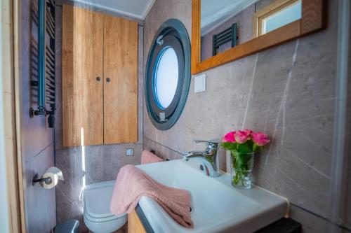 a bathroom with a sink and a vase of pink flowers at Luxuriöses Hausboot Roma Woma D13 in Fürstenberg