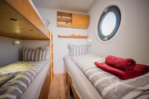 a small bedroom with two beds and a window at Luxuriöses Hausboot Roma Woma D13 in Fürstenberg