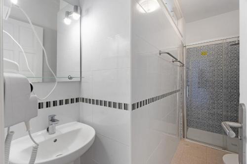 a white bathroom with a shower and a sink at Apartamentos Playa Azul - 8 in Vallehermoso