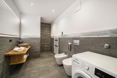 a bathroom with a toilet and a washing machine at Waldes Duft Apartment - Patleidhof in Naturno