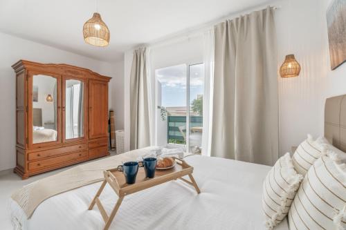 a white bedroom with a bed with a table on it at Sunlit Modern Stay in Arona