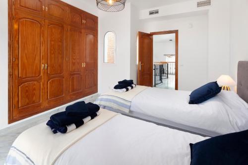 two beds in a room with white walls and blue pillows at Casa Montelado in Mijas