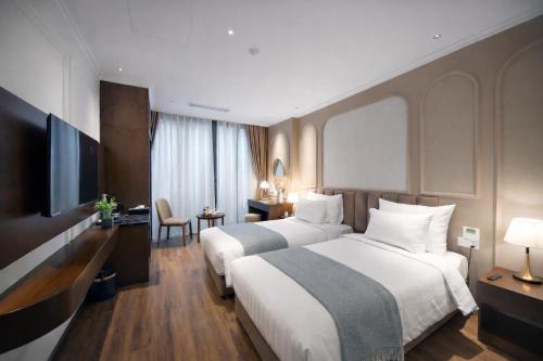 a hotel room with two beds and a television at L'amant de Hanoi Hotel in Hanoi
