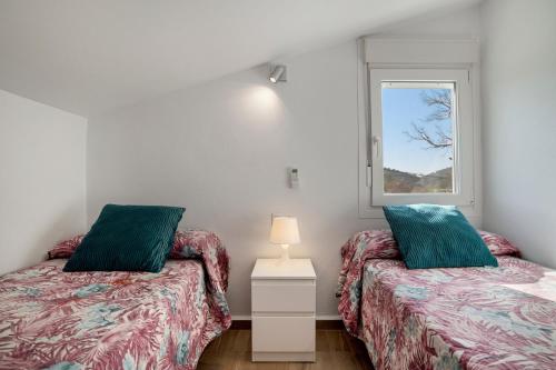 two twin beds in a room with a window at Casa El Buda in Vejer de la Frontera