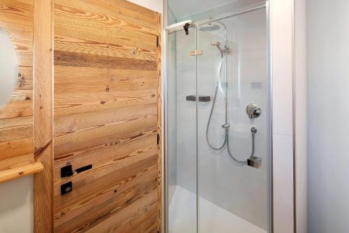 een douche in een badkamer met een houten wand bij Cesa Pattis in Mazzin