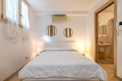 a white bedroom with a bed and two mirrors at L'Angolo Monolocale- Porto Torres in Porto Torres