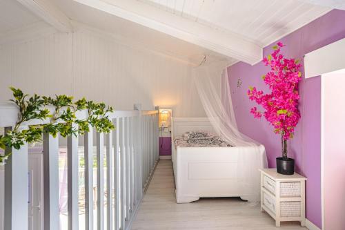 una camera da letto con culla bianca e pareti rosa di Gite l'Escapade a Saint-Nazaire-sur-Charente