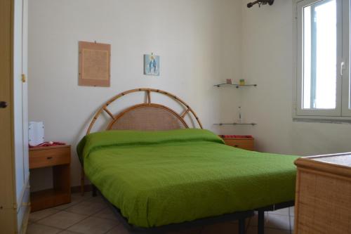 a bed with a green blanket on it in a room at Appartamento Ll06 a 60m dal mare in San Foca