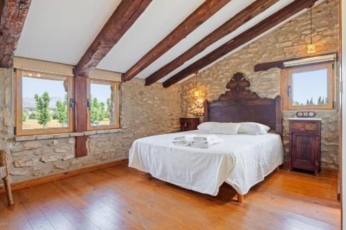 a bedroom with a large bed in a stone wall at Lo Molí de la Jòrdia in Tortosa