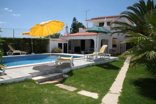 a house with a swimming pool with chairs and an umbrella at Quinta da Eira in Lagoa