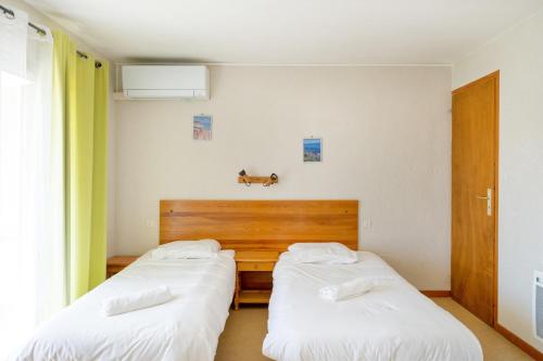 two beds in a room with white sheets at Les Mimosas - Appartement 07 in Cazaubon