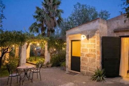a patio with a table and chairs at night at Masseria De Donno in Specchia