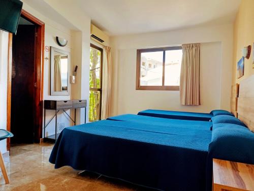 a bedroom with a blue bed and a window at Hostal Horizonte in San Antonio