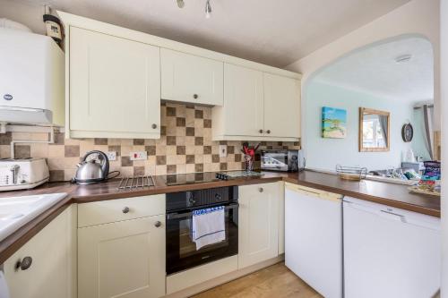 a kitchen with white cabinets and a stove top oven at Dolphin Cottage - Short walk to Poole Quay with Private Garden in Poole