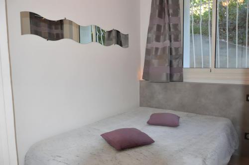 a bed with purple pillows on it in a bedroom at T2 Le Bougainvillier Cassis in Cassis