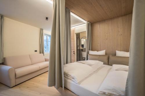a bedroom with a large bed and a couch at Avia Living Teresa in Brunico