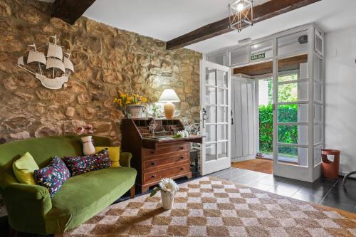 a living room with a green couch and a stone wall at Apartamento 4 Casa Las Indianas in Selores