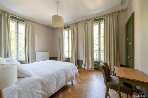 a bedroom with a bed and a desk and windows at Maison Bourgeoise de caractère in Tarare