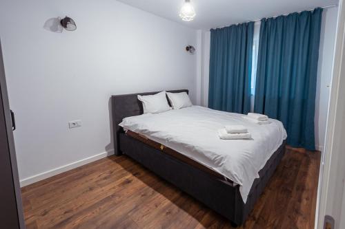 a bedroom with a large bed with blue curtains at Confort Apartment in Iaşi