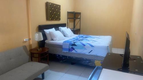 a bedroom with a bed and a desk with a television at Harry & Mimin Homestay in Gorontalo