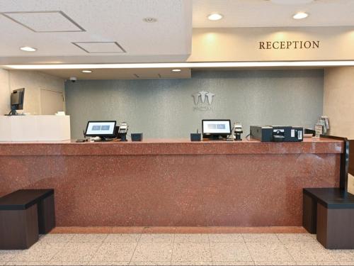 a hotel reception counter with two computers on it at Sanco Inn Kuwana Ekimae in Kuwana
