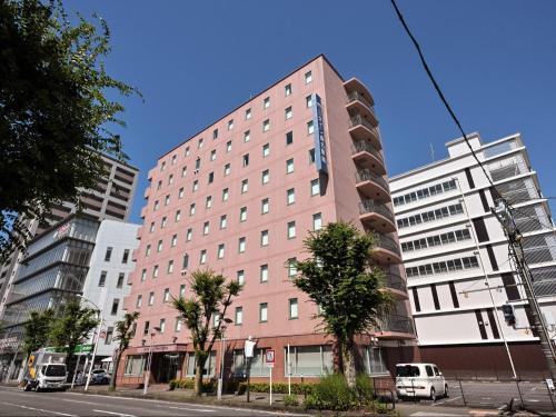 a tall pink building on a city street at Sanco Inn Kuwana Ekimae in Kuwana