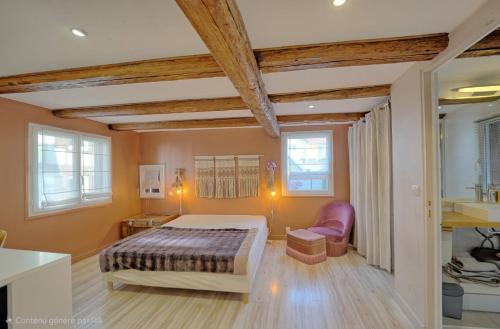 a bedroom with a bed and a chair and windows at Meublés de tourisme Griotte et Cannelle in Bergbieten