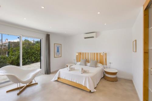 a bedroom with a white bed and a white chair at Villa Linda in Punta Prima