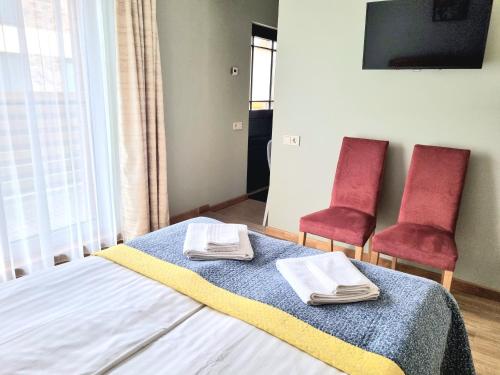 a bedroom with two chairs and a bed with towels on it at GMM Namai in Palanga