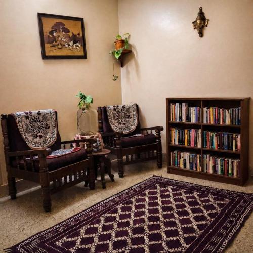 a living room with two chairs and a book shelf at The Timeless Mysuru bungalow in Mysore