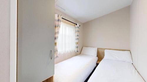 two beds in a small room with a window at Unity Seven Lakes in Crowle