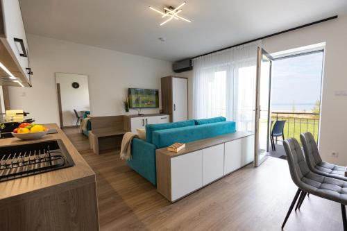 a living room with a blue couch and a kitchen at Pelso Lodge Alsóörs in Alsóörs