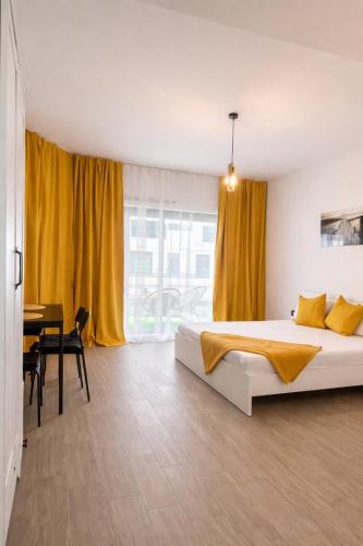 a bedroom with a bed with yellow curtains and a table at Ametist in Mamaia
