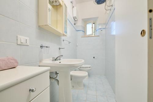 a white bathroom with a sink and a toilet at Mare Etrusco 4 in Populonia