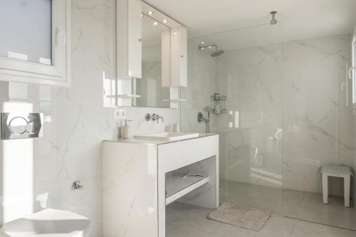a white bathroom with a sink and a shower at Aegean Villas Ios in Ios Chora