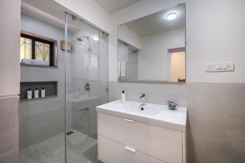 a white bathroom with a sink and a shower at SaffronStays Sparrow's Nest in Mahabaleshwar
