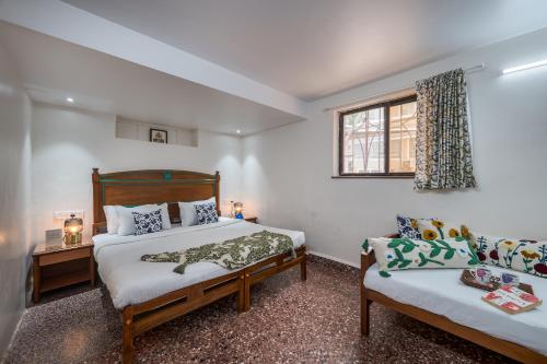 a bedroom with two beds and a window at SaffronStays Sparrow's Nest in Mahabaleshwar