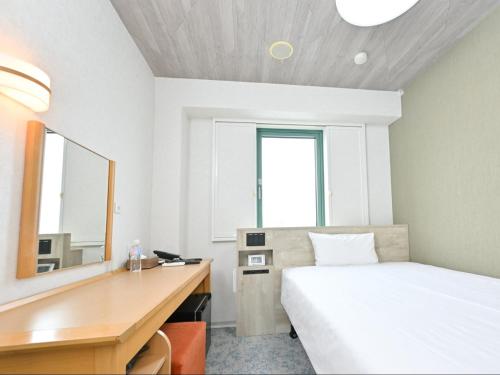a bedroom with a bed and a desk with a mirror at Sanco Inn Kuwana Ekimae in Kuwana